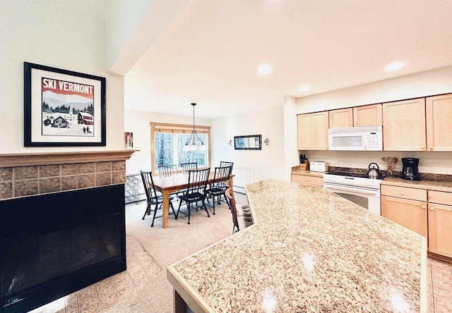 kitchen with hanging light fixtures, a center island, light brown cabinets, and white appliances