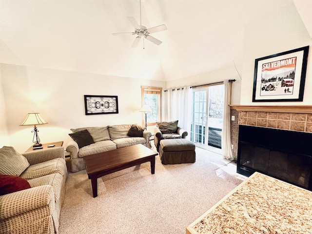 living room with a tile fireplace, carpet, lofted ceiling, and ceiling fan