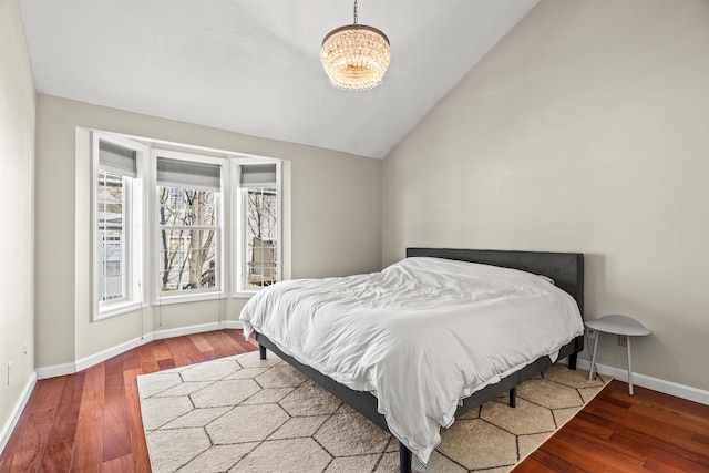 bedroom featuring hardwood / wood-style flooring, vaulted ceiling, and a chandelier