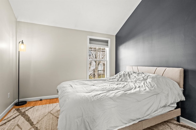 bedroom with vaulted ceiling and light wood-type flooring