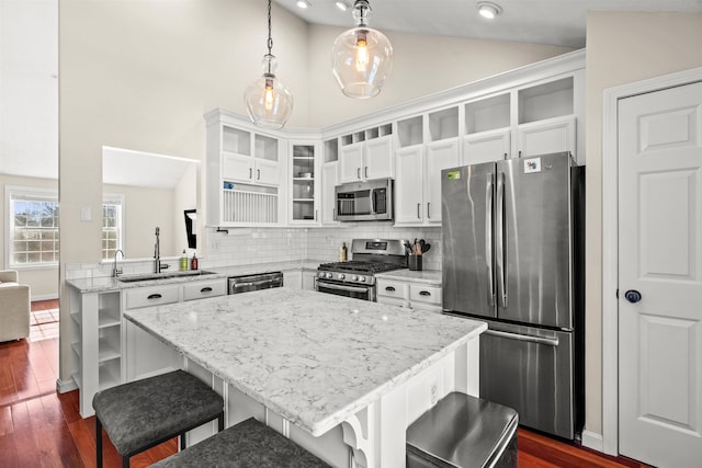 kitchen with lofted ceiling, sink, a breakfast bar area, appliances with stainless steel finishes, and pendant lighting