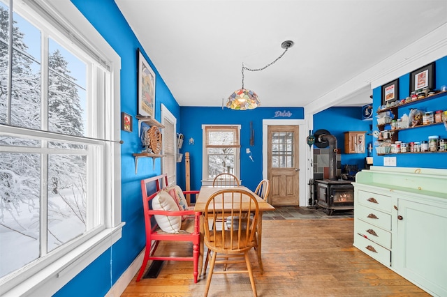 dining space featuring hardwood / wood-style flooring, plenty of natural light, and a wood stove