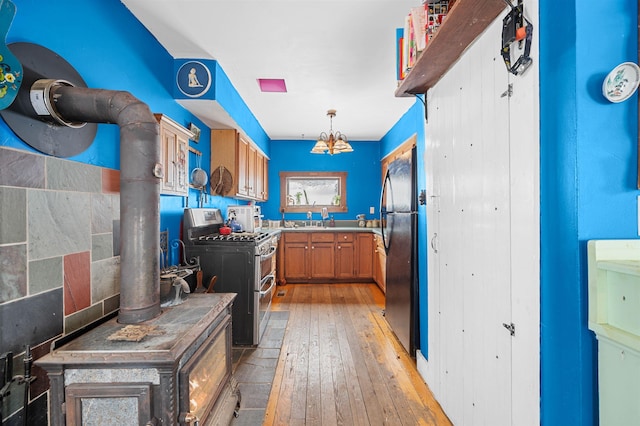 kitchen with decorative light fixtures, black refrigerator, double oven range, a notable chandelier, and light hardwood / wood-style floors