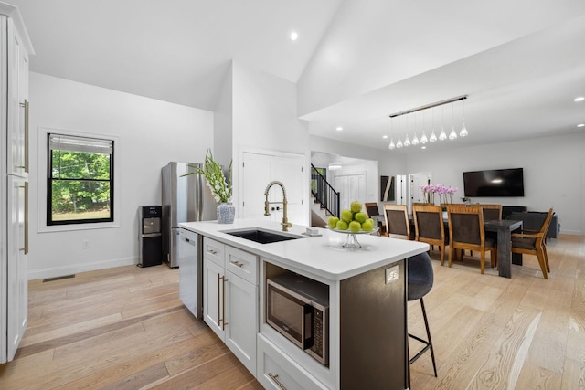 kitchen featuring sink, stainless steel appliances, white cabinets, and a center island with sink