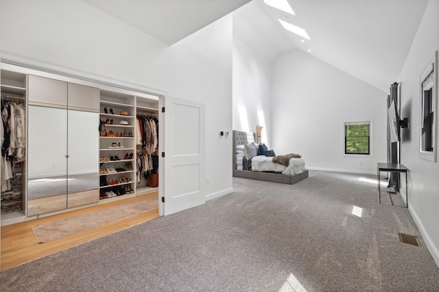 interior space featuring carpet floors, a skylight, and high vaulted ceiling