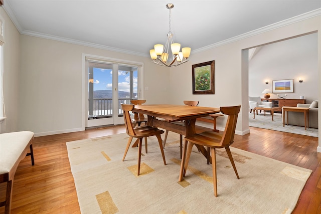 dining room with hardwood / wood-style floors, ornamental molding, and a chandelier