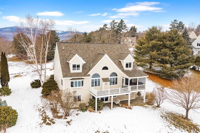 snow covered rear of property featuring a sunroom