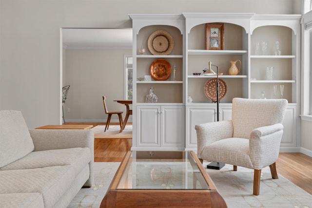 sitting room featuring ornamental molding and light wood-type flooring