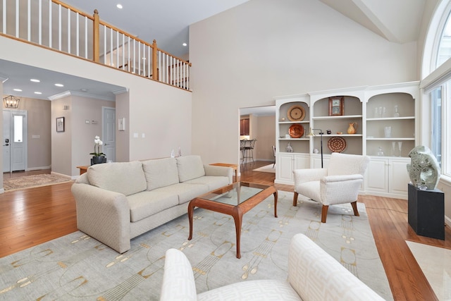 living room featuring ornamental molding, a high ceiling, and light wood-type flooring