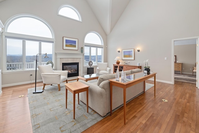 living room with high vaulted ceiling, light hardwood / wood-style flooring, and a tile fireplace