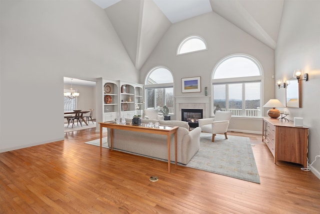 living room with high vaulted ceiling, a healthy amount of sunlight, a fireplace, and light hardwood / wood-style flooring