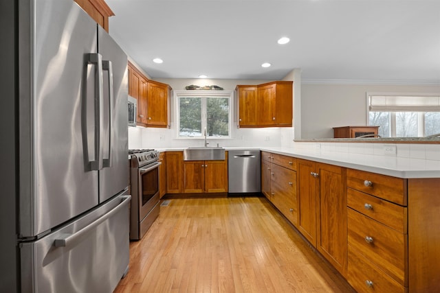 kitchen with sink, light wood-type flooring, kitchen peninsula, stainless steel appliances, and backsplash