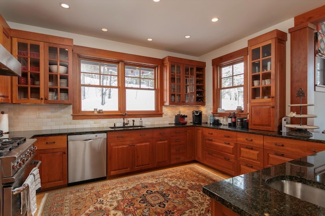 kitchen featuring appliances with stainless steel finishes, sink, dark stone countertops, and backsplash