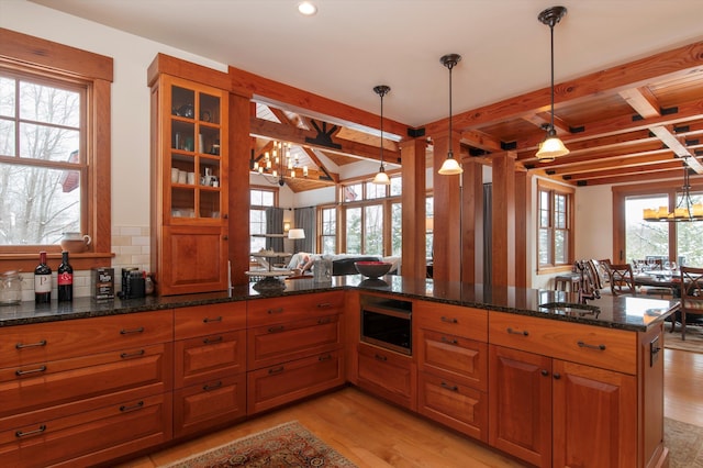 kitchen with pendant lighting, dark stone countertops, light hardwood / wood-style floors, kitchen peninsula, and an inviting chandelier