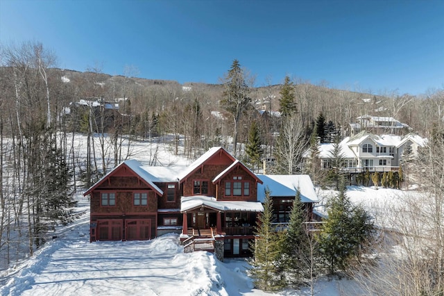 snow covered back of property featuring a mountain view