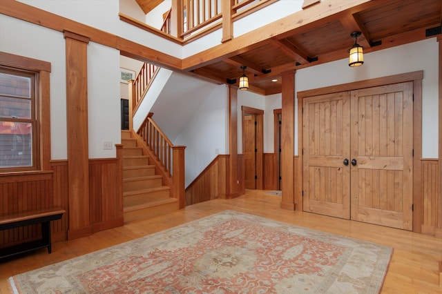 foyer with wood ceiling, wood walls, beam ceiling, and light hardwood / wood-style floors