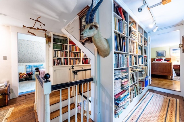 corridor with hardwood / wood-style floors and rail lighting