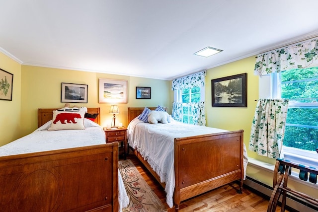 bedroom featuring ornamental molding, a baseboard heating unit, and hardwood / wood-style floors