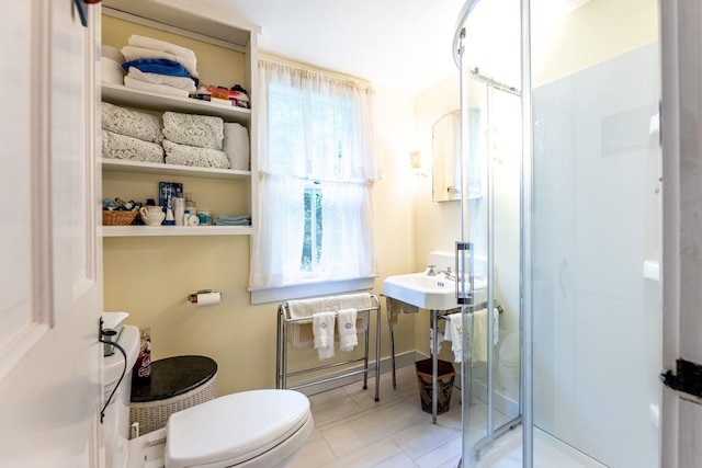 bathroom featuring sink, a shower with shower door, and toilet