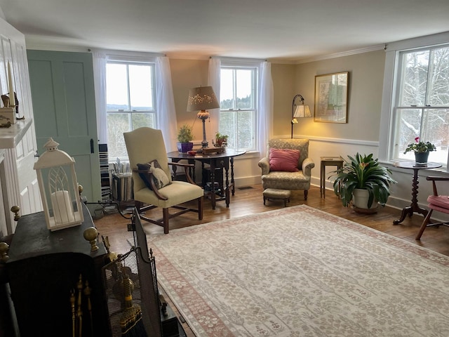 living area with wood-type flooring and ornamental molding