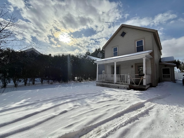 snow covered rear of property with a porch