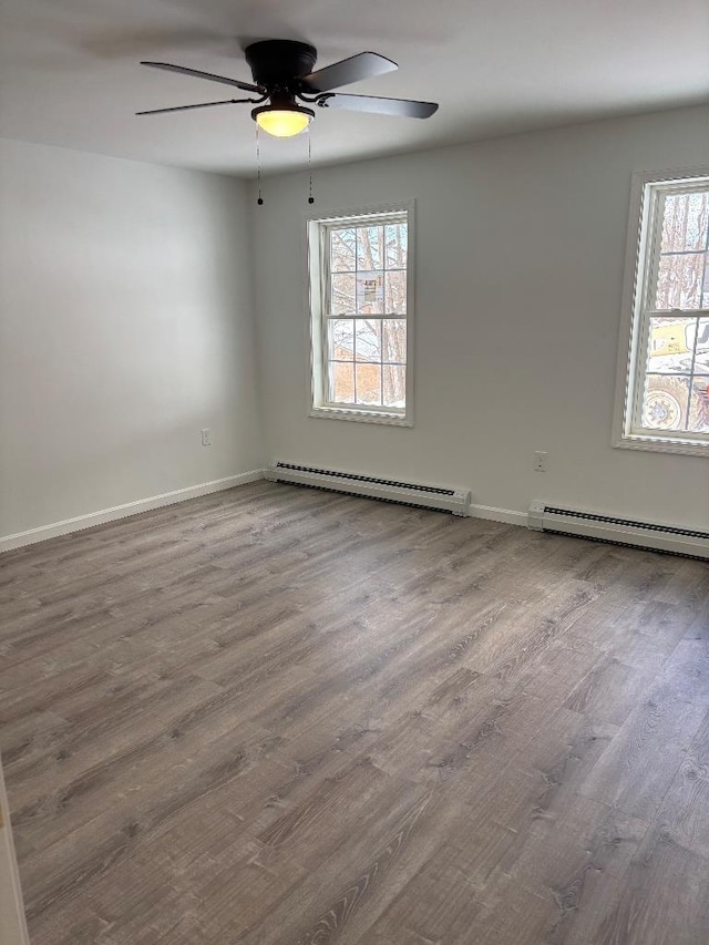 spare room featuring baseboard heating, ceiling fan, and hardwood / wood-style floors