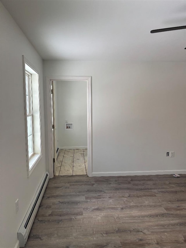 spare room with dark hardwood / wood-style flooring, a baseboard heating unit, and ceiling fan