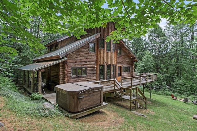 back of property featuring a hot tub, a wooden deck, and a lawn