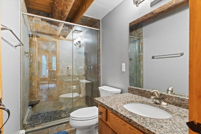 bathroom featuring vanity, a shower with shower door, and toilet