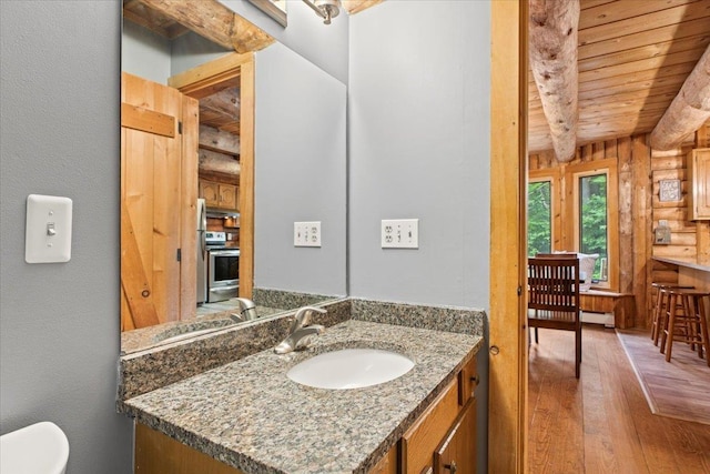 bathroom with wood ceiling, rustic walls, vanity, wood-type flooring, and beamed ceiling