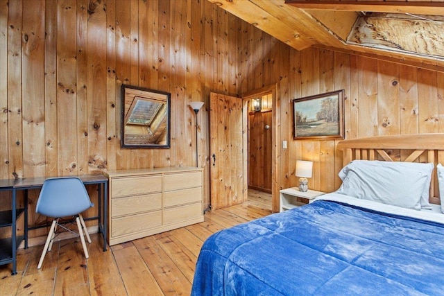 bedroom with lofted ceiling, wooden walls, and light wood-type flooring