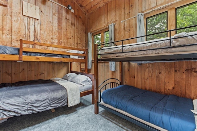 carpeted bedroom with lofted ceiling and wooden walls