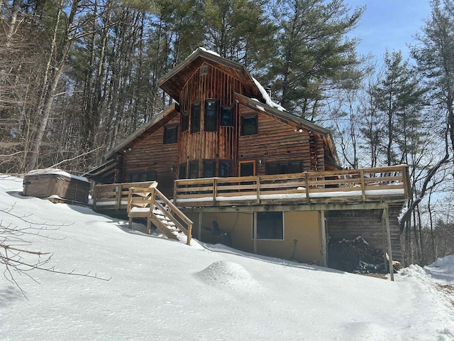 snow covered rear of property featuring a deck