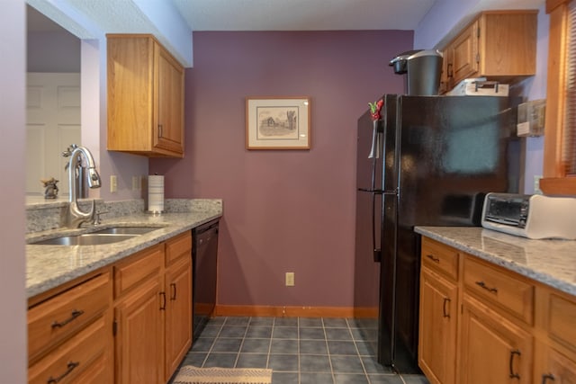 kitchen featuring sink, black appliances, dark tile patterned flooring, and light stone countertops