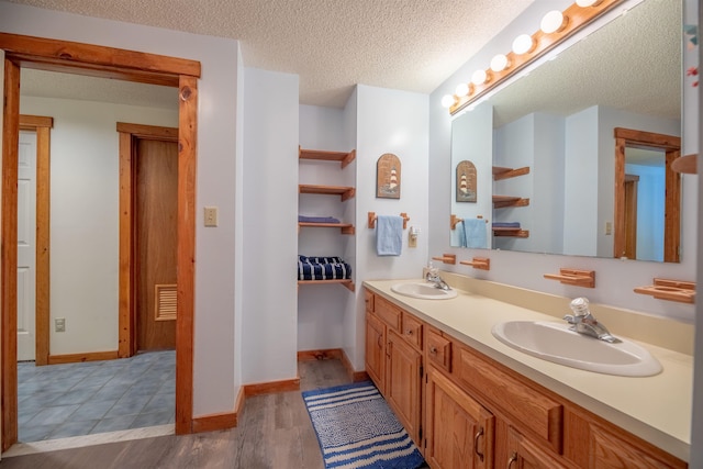 bathroom featuring vanity, wood-type flooring, and a textured ceiling