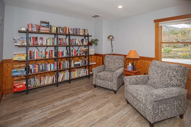 sitting room featuring wood-type flooring and wooden walls