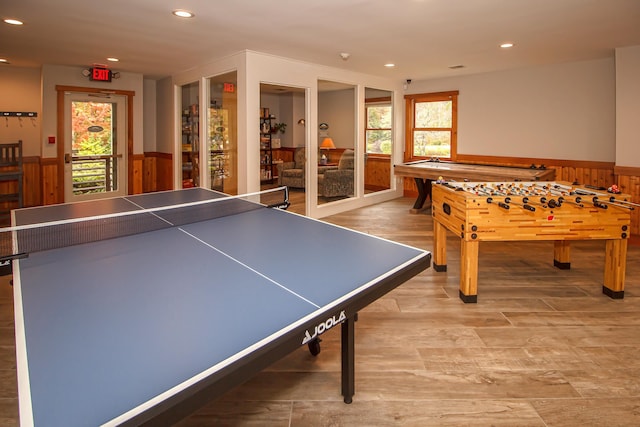 rec room featuring wood walls, light hardwood / wood-style flooring, and a wealth of natural light