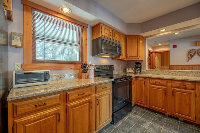 kitchen featuring dark tile patterned floors, light stone countertops, and black appliances