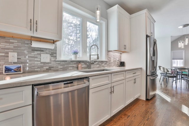 kitchen featuring sink, dark wood-type flooring, appliances with stainless steel finishes, hanging light fixtures, and white cabinets