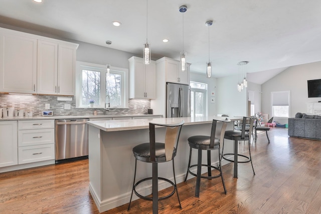 kitchen with stainless steel appliances, a kitchen island, sink, and white cabinets