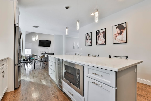 kitchen with built in microwave, pendant lighting, a kitchen bar, and white cabinets