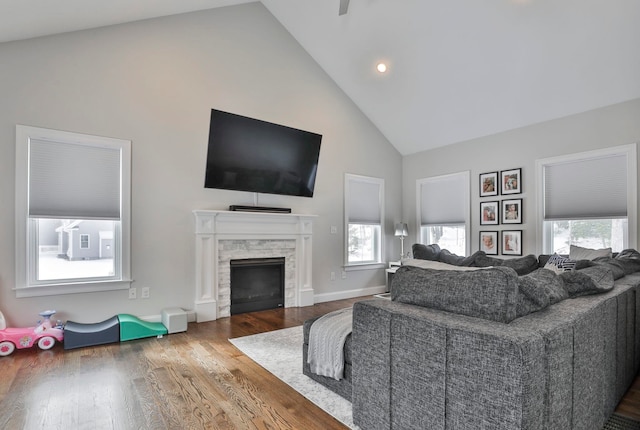 living room with cooling unit, high vaulted ceiling, a stone fireplace, and hardwood / wood-style floors