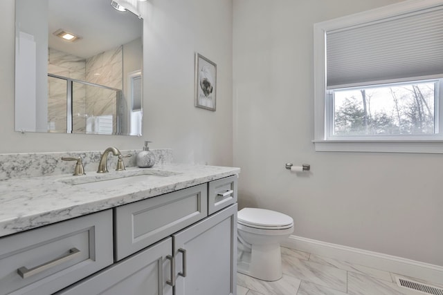 bathroom with toilet, vanity, and a shower with shower door