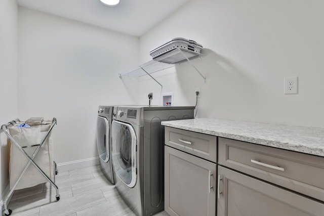 clothes washing area with cabinets and washing machine and clothes dryer