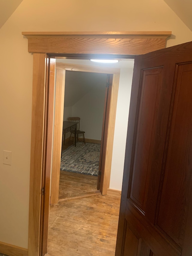 hall with lofted ceiling and light wood-type flooring