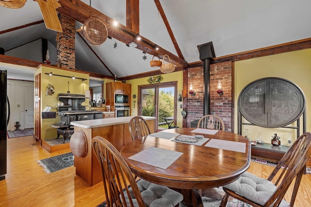 dining area with beam ceiling, high vaulted ceiling, light hardwood / wood-style flooring, and a wood stove