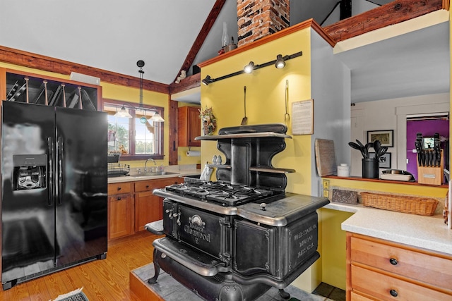 kitchen with sink, decorative light fixtures, vaulted ceiling, black refrigerator with ice dispenser, and light hardwood / wood-style floors