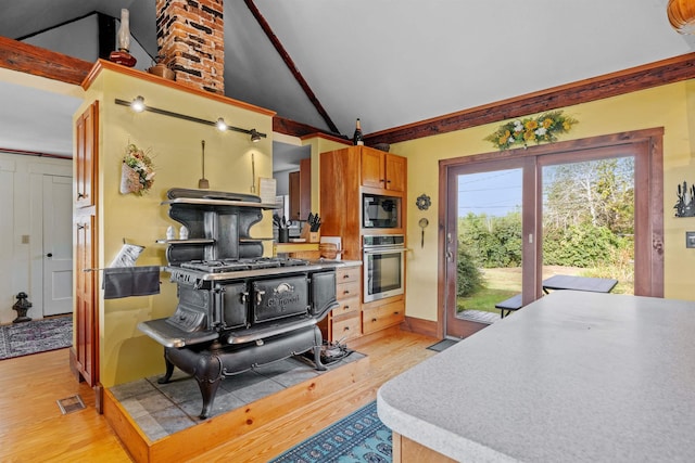 kitchen featuring black microwave, high vaulted ceiling, stainless steel oven, and light wood-type flooring