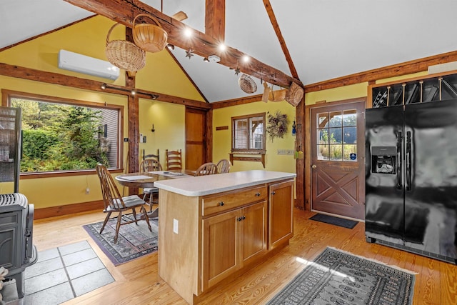 kitchen featuring a center island, a wall mounted AC, black fridge with ice dispenser, decorative light fixtures, and light wood-type flooring