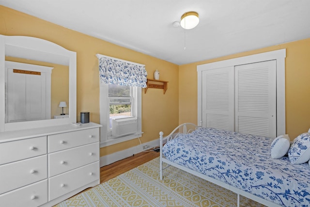 bedroom with cooling unit, a closet, and light hardwood / wood-style flooring